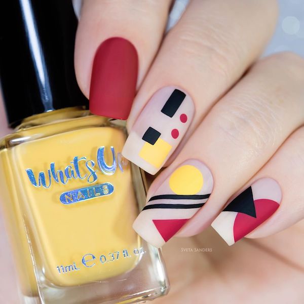 Elegant French manicures with black, red, and yellow abstract geometric shapes 