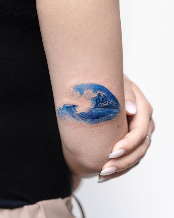Blue wave small tattoo on outer forearm