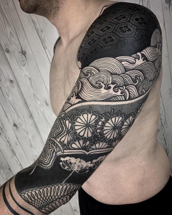 Upper arm blackwork with wave and floral designs