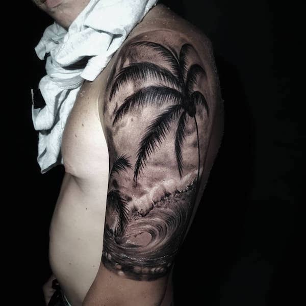 Upper arm tattoo of a palm branch and a wave