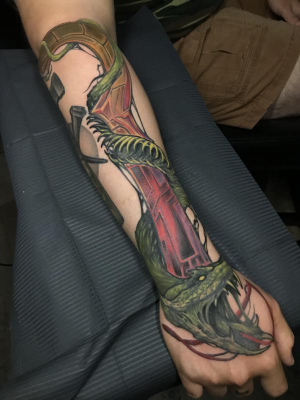 A green viper snake entwined with branch forearm tattoo