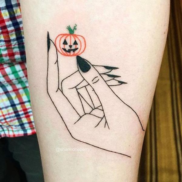 A hand holding a pumpkin outline