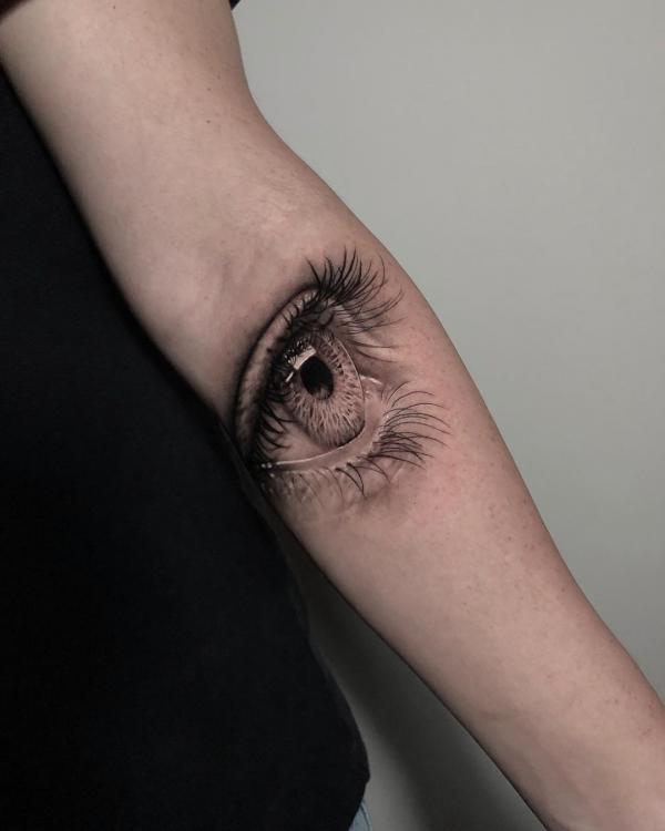 Minimalist evil eye tattoo on the elbow