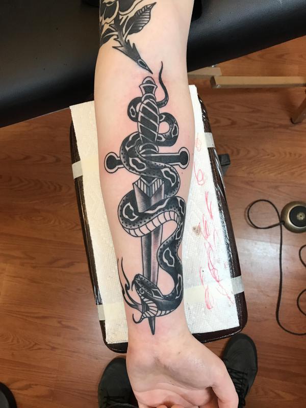 Black and white traditional snake and dagger forearm tattoo