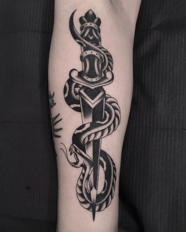 Black and white traditional snake and dagger forearm tattoo