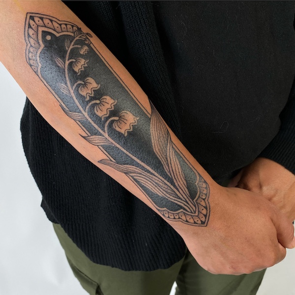 Blackout tattoo with Lily of the Valley on forearm