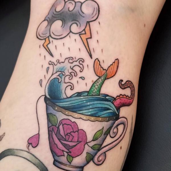 Cloud lightning bolts and a mermaid tail in bowl with wave tattoo
