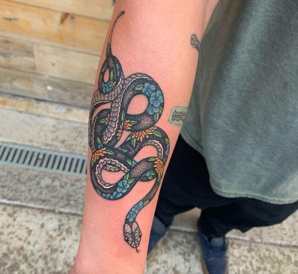 Coiled floral snake tattoo on forearm