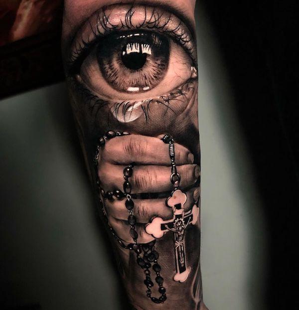Eye with teardrop and hand with rosary