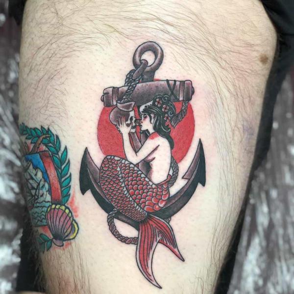 Mermaid holding a skull on anchor tattoo