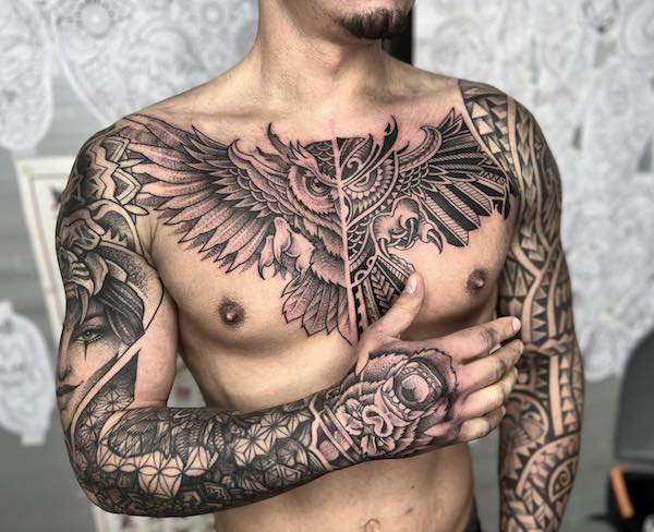 Realistic and tribal symmetrical owl tattoo on chest