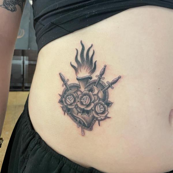 Side tattoo of a sacred heart with roses and dagger