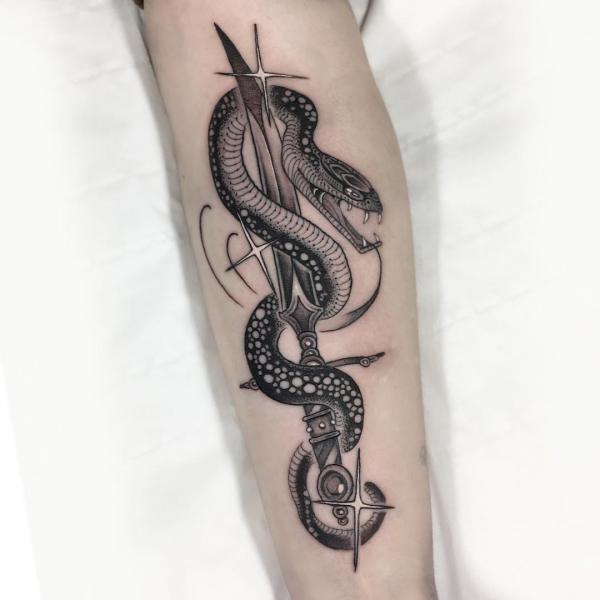 Snake moving on a dagger forearm tattoo