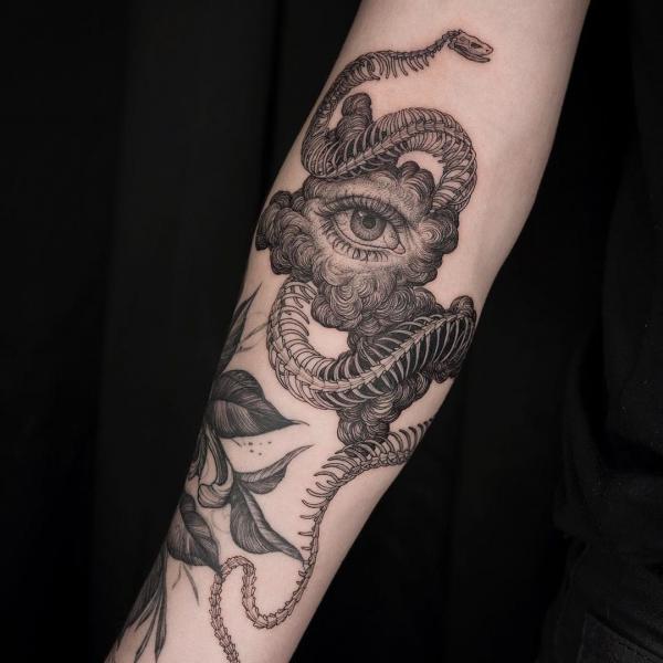 Snake skeleton with eye tattoo on forearm