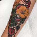 Traditional snake and hibiscus tattoo forearm
