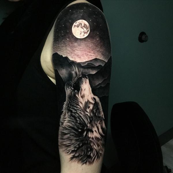 A wolf howling at the moon arm tattoo