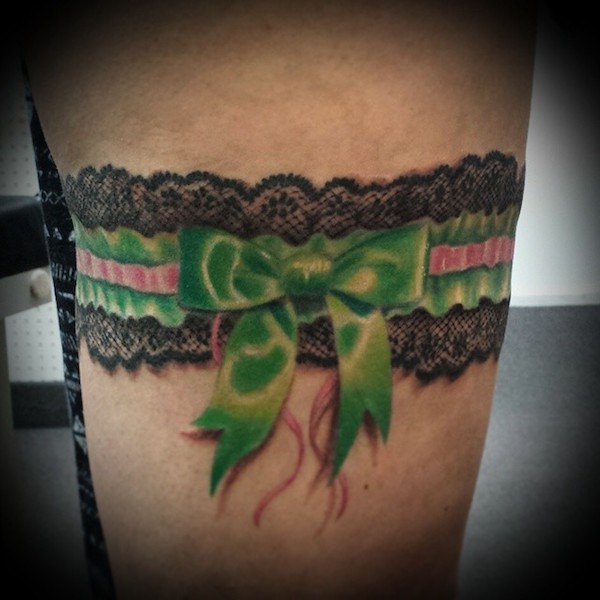 Black lace garter encircled with green ribbon with bow