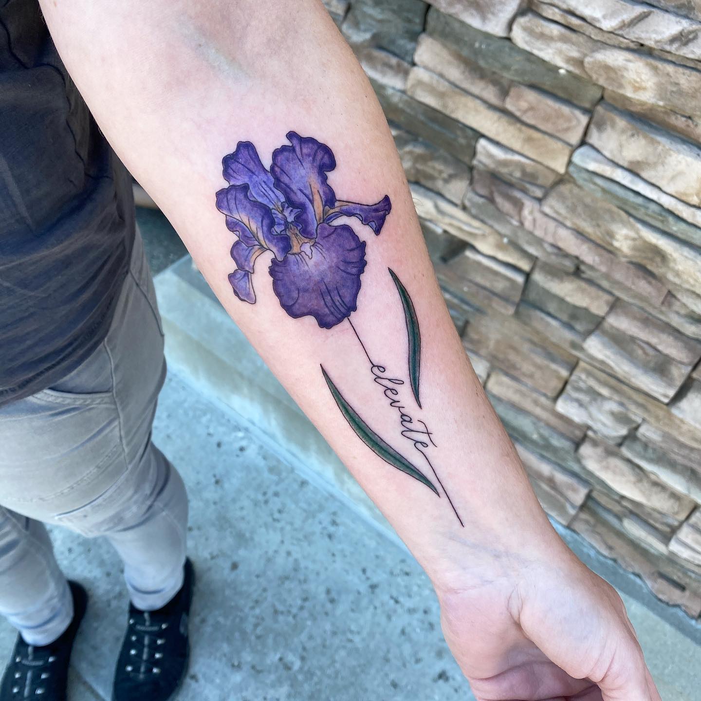 Purple iris with inspiring word elevate on forearm