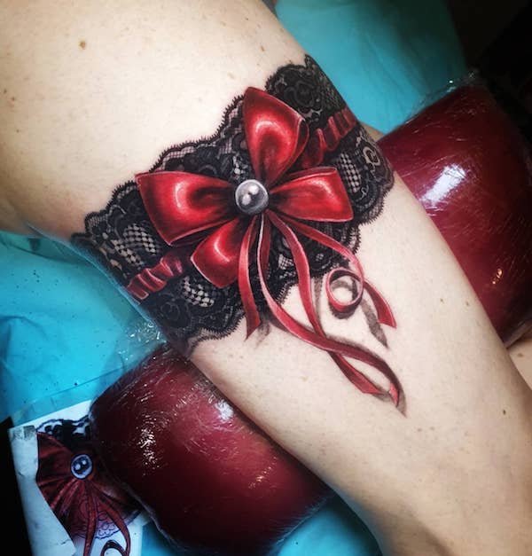 Realistic red bow garter tattoo