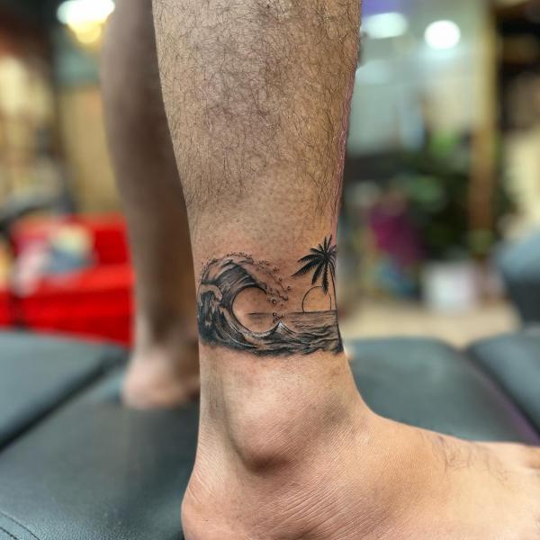 Wave ankle tattoo with sun and palm tree