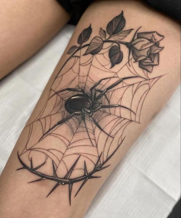 A black spider in the center of its web encircled with rose and thorn