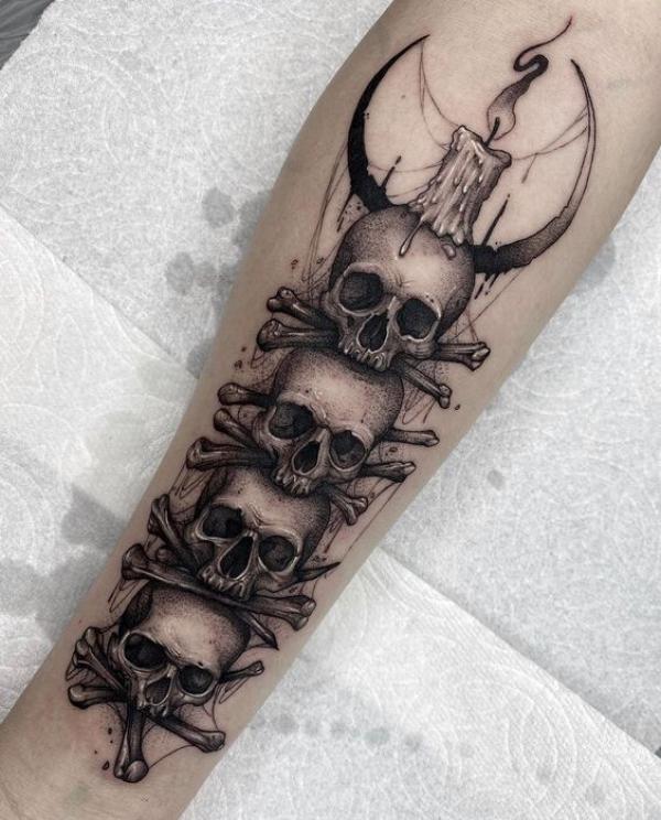 A candle burning atop four skulls with crossbones and crescent moon