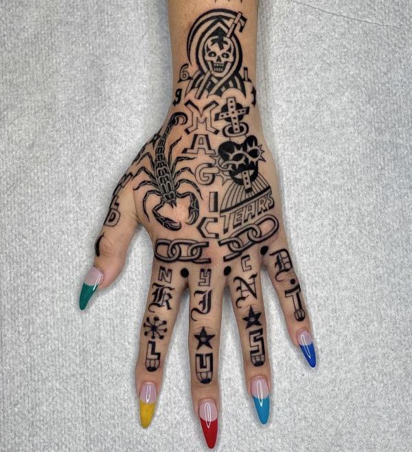 Intricate hand tattoo with scorpion skull cross chain and letters