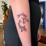 Red and grey two koi fish forearm tattoo