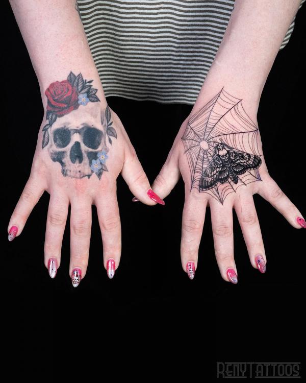 Skull with rose and spider web with moth hands tattoo