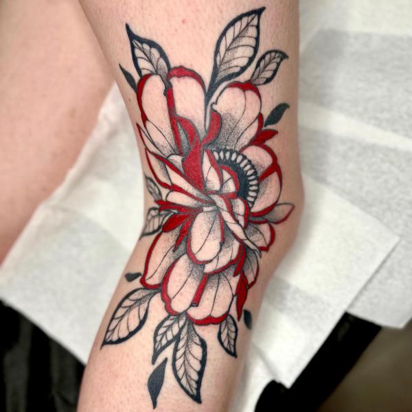 Black and red rose tattoo on the side of knee