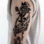 Black traditional skeleton hand holding a rose