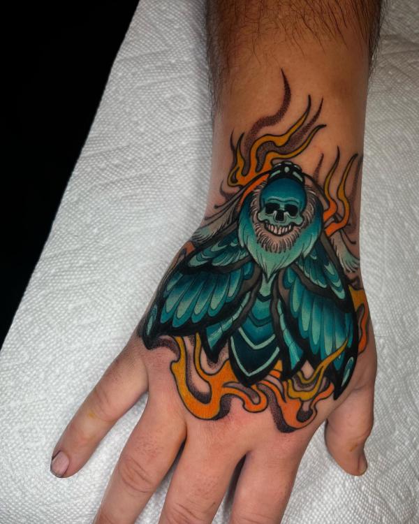 Flaming death moth hand tattoo