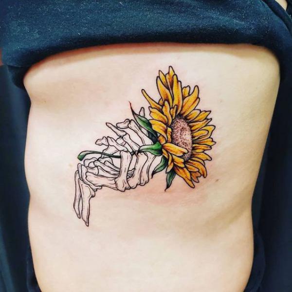 Skeleton hand holding a sunflower