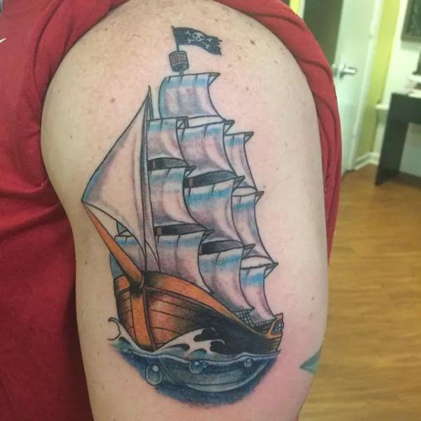 Small colored pirate ship tattoo on upper arm