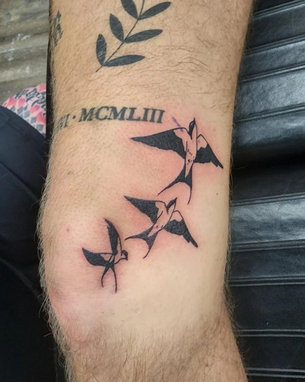 Three flying swallows tattoo around the knee