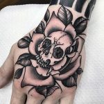Traditional black ink skull with rose tattoo on hand
