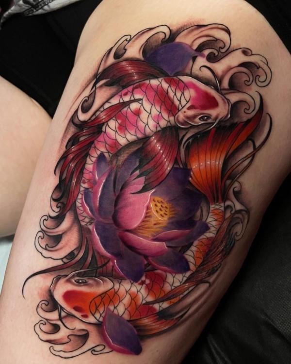 Two fish swimming in water around lotus flower tattoo