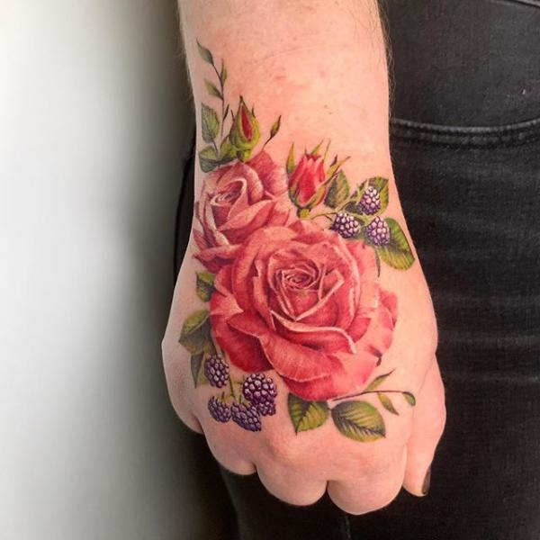 Vibrant red roses with cherry hand tattoo