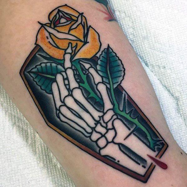 Yellow rose and skeleton hand in coffin