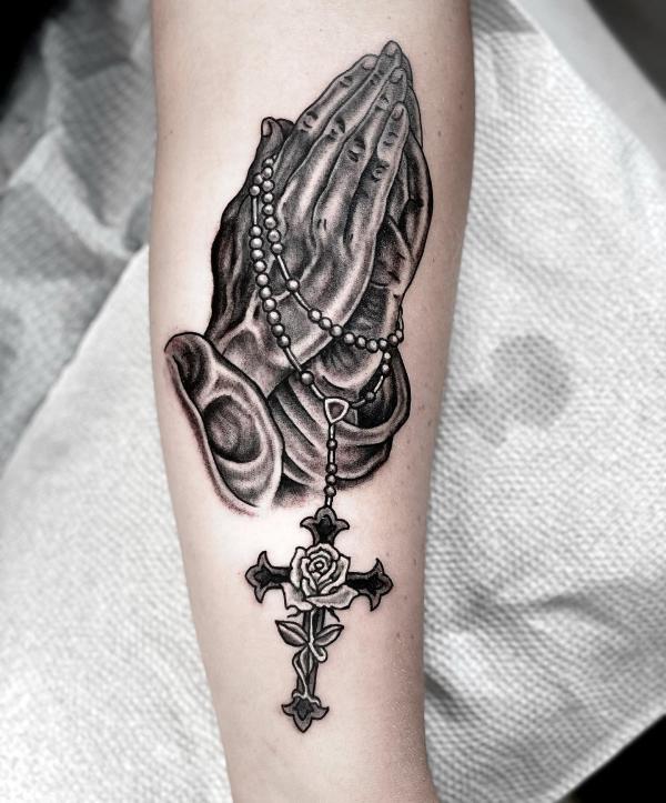 praying hands with rosary and cross entwined with roses