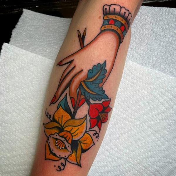 A hand holding daffodil forearm tattoo