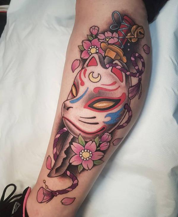 A dagger pierced kitsune mask lower leg tattoo