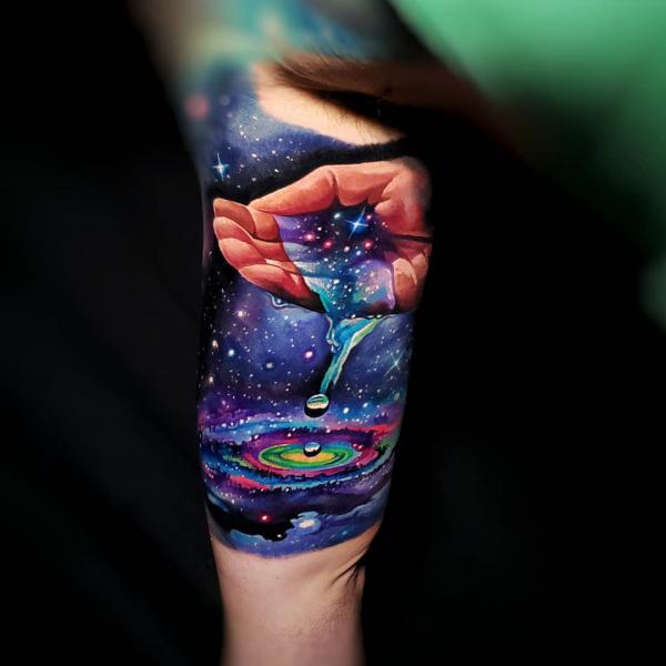 A hand holding galaxy water tattoo