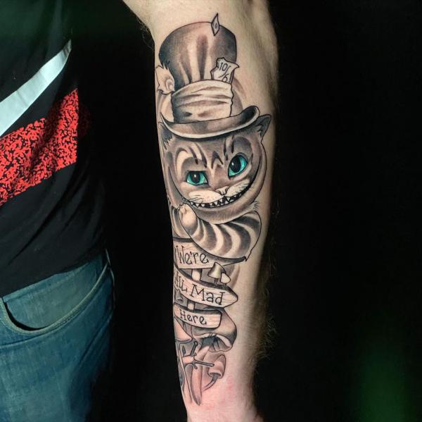 Black and grey Cheshire Cat with words were all mad here tattoo forearm