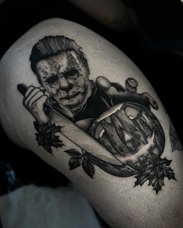 Black and grey Michael Myers holding a knife to a carved pumpkin