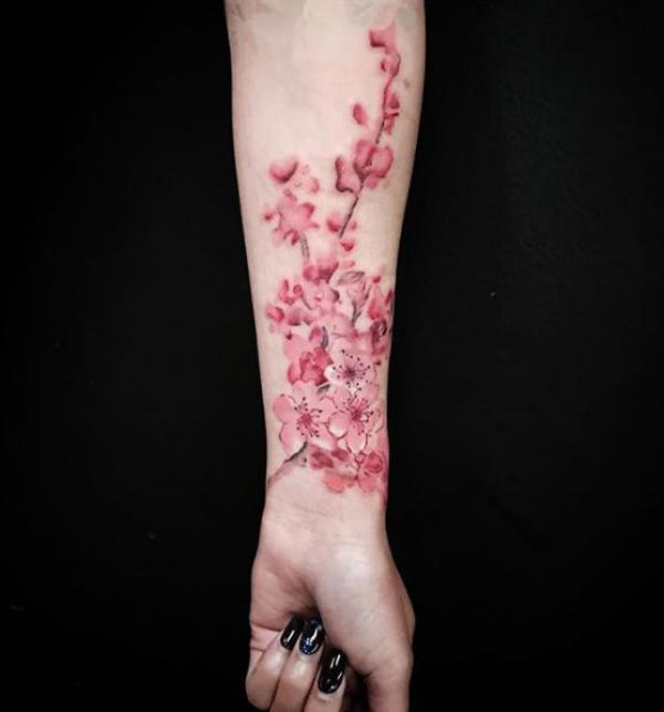 Pink cherry blossom tattoo on inner forearm