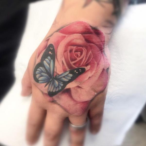 Pink rose and butterfly hand tattoo
