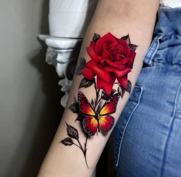 Vibrant red rose and butterfly forearm tattoo
