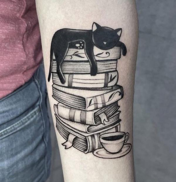 A black cat sleeping on a pile of books