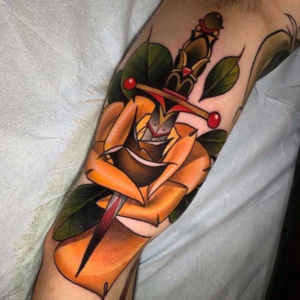 A dagger pierced a yellow rose tattoo